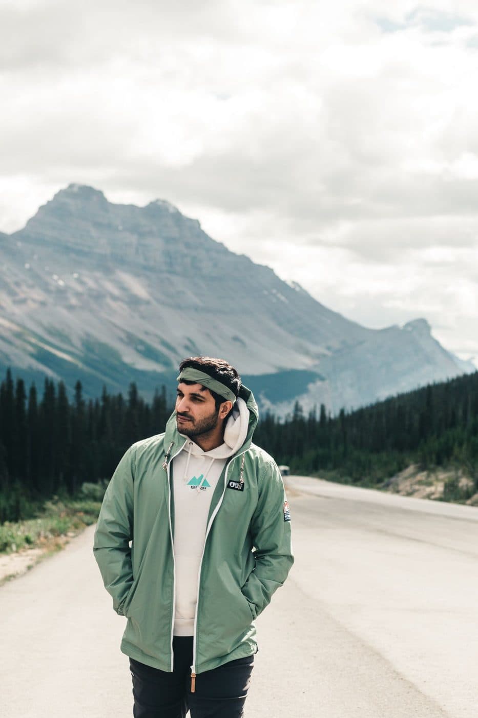 Sage green zip jacket worn outdoors with mountains behind