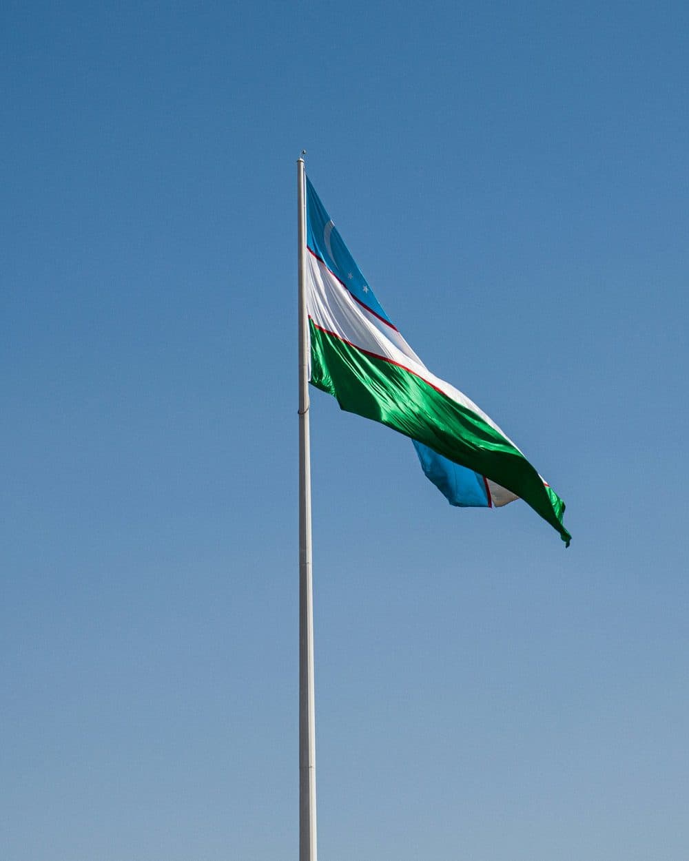Blue, white and green Uzbekistan flag waving on a pole