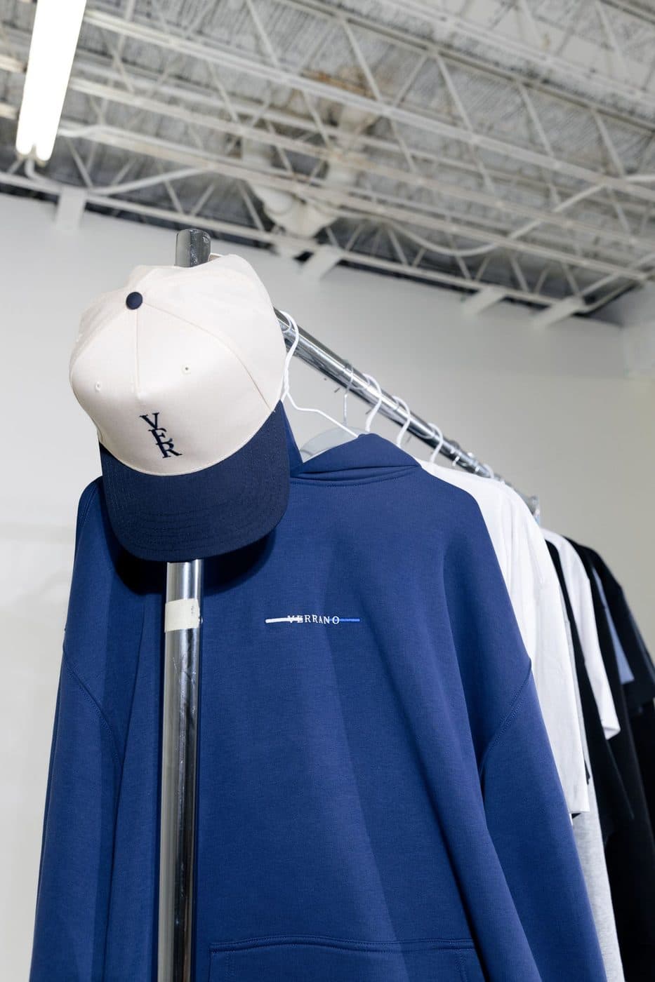 White and navy baseball cap hanging on a clothing rack