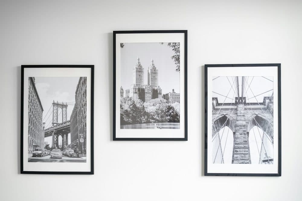 Three framed black-and-white city prints on a white wall