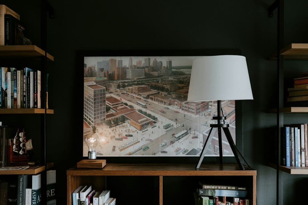 Framed city art print on a shelf beside a lamp